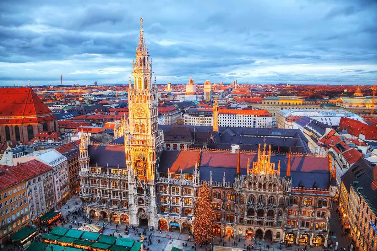 Luftaufnahme des historischen Marienplatzes in München mit dem beleuchteten neugotischen Turm des Neuen Rathauses und dem Christkindlmarkt